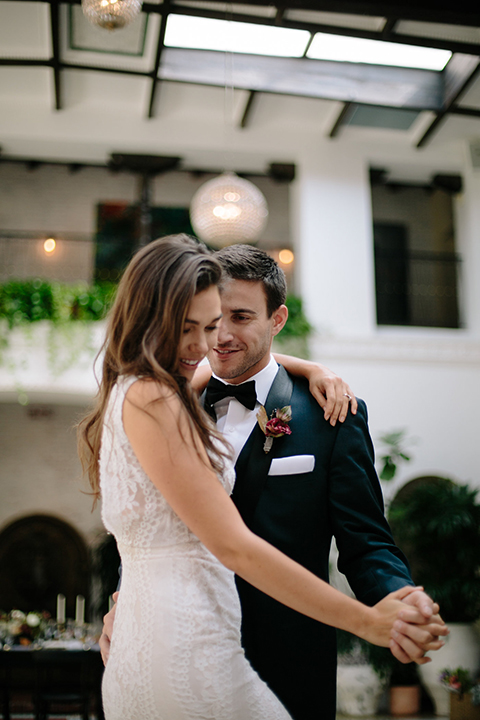 Southern-california-wedding-at-the-ebell-of-long-beach-bride-and-groom-dancing-and-smiling-bride-wearing-a-lace-a-line-dress-with-straps-and-hair-in-loose-down-waves-and-groom-in-navy-tux-with-black-trim-and-black-bowtie