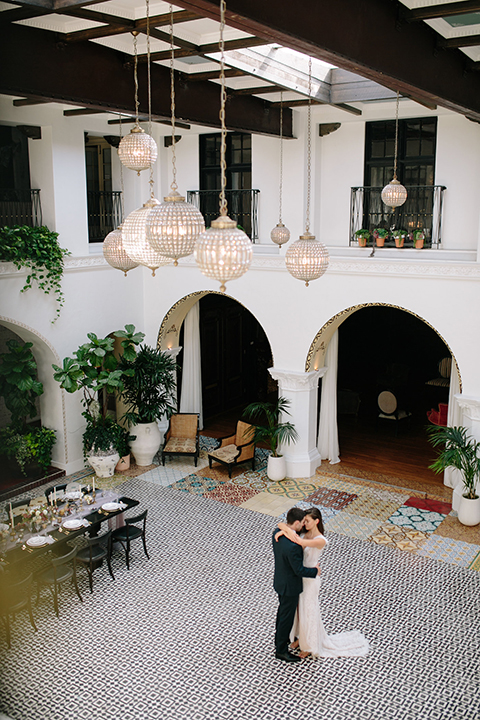 Southern-california-wedding-at-the-ebell-of-long-beach-bride-and-groom-dancing-far-away-bride-wearing-a-lace-a-line-dress-with-straps-and-hair-in-loose-down-waves-and-groom-in-navy-tux-with-black-trim-and-black-bowtie