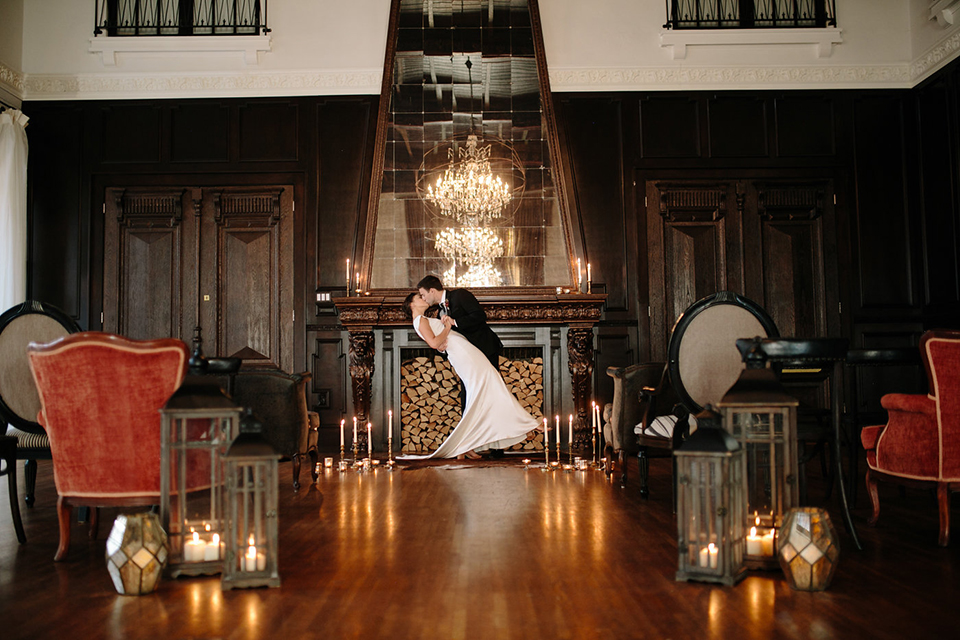 Southern-california-wedding-at-the-ebell-of-long-beach-ceremony-bride-and-groom-kissing-bride-wearing-a-lace-a-line-dress-with-straps-and-hair-in-loose-down-waves-and-groom-in-navy-tux-with-black-trim-and-black-bowtie