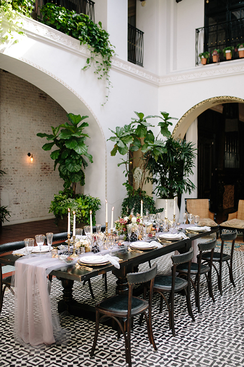 Southern-california-wedding-at-the-ebell-of-long-beach-table-set-up-with-chairs-wooden-chairs-and-table-with-white-and-chamange-toned-linnens-and-greenery-as-floral-arrangements