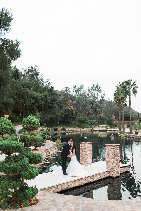 los-willows-wedding-bride-and-groom-kissing-on-dock-bride-alone-final-bride-in-a-tulle-ballgown-with-sleeves-groom-in-a-traditional-black-tuxedo-with-black-bow-tie-and-tuxed-shoes