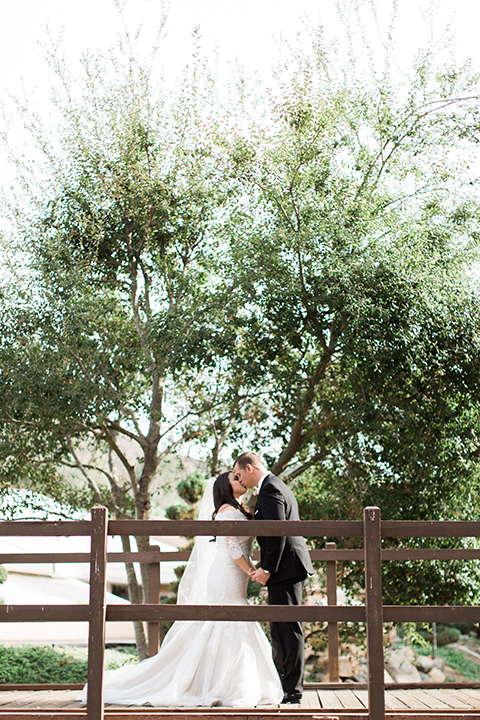 los-willows-wedding-bride-and-groom-on-bridge-bride-in-a-tulle-ballgown-with-sleeves-groom-in-a-traditional-black-tuxedo-with-black-bow-tie-and-tuxed-shoes