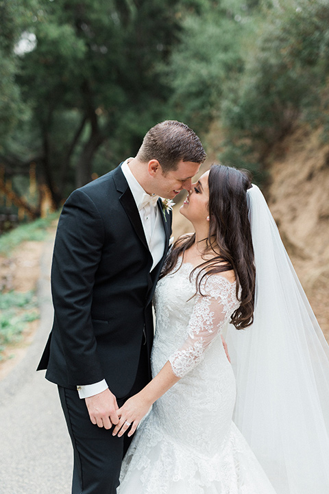 los-willows-wedding-bride-and-groom-standing-by-kissing-bride-in-a-tulle-ballgown-with-sleeves-groom-in-a-traditional-black-tuxedo-with-black-bow-tie-and-tuxed-shoes