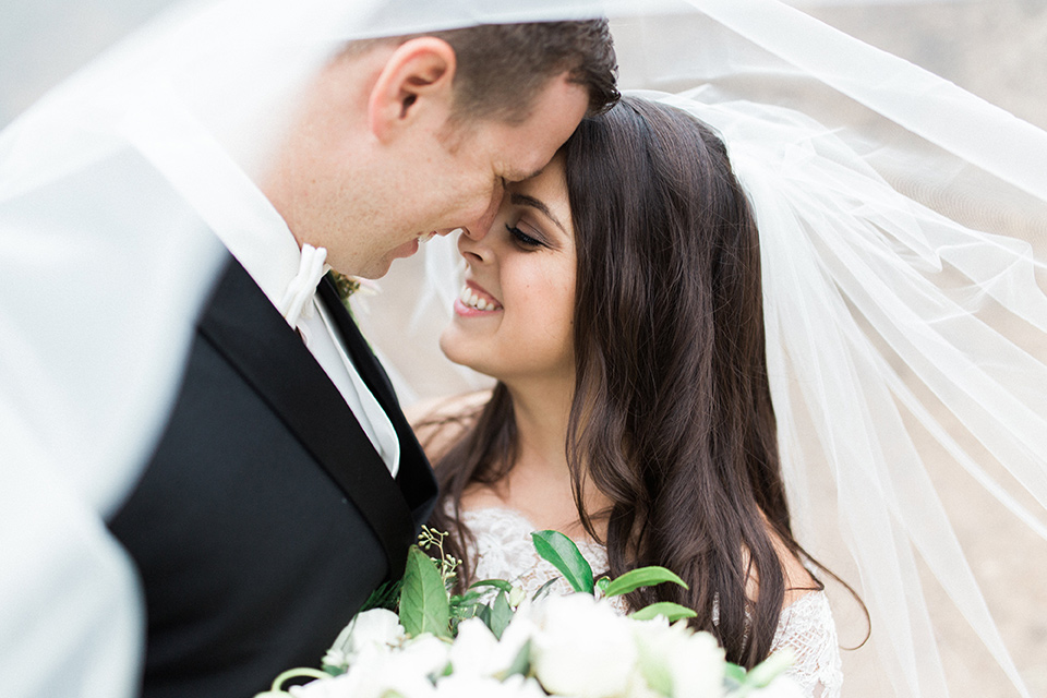 los-willows-wedding-bride-and-groom-under-veil-bride-in-a-tulle-ballgown-with-sleeves-groom-in-a-traditional-black-tuxedo-with-black-bow-tie-and-tuxed-shoes