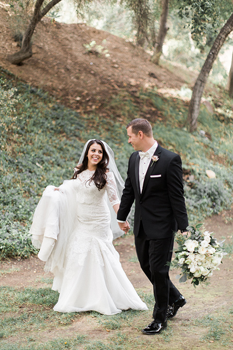 los-willows-wedding-bride-and-groom-walking-bride-in-a-tulle-ballgown-with-sleeves-groom-in-a-traditional-black-tuxedo-with-black-bow-tie-and-tuxed-shoes