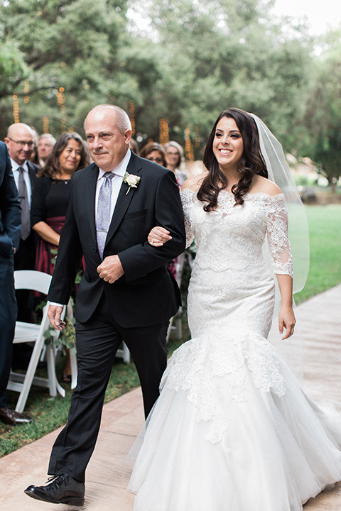 los-willows-wedding-bride-walking-down-aisle-bride-in-a-tulle-ballgown-with-sleeves-groom-in-a-traditional-black-tuxedo-with-black-bow-tie-and-tuxed-shoes