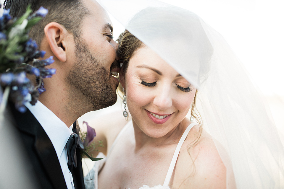 Avenue-of-the-arts-wedding-bride-and-groom-close-up-under-veil-bride-in-tulle-ball-gown-with-beaded-bodice-and-beaded-headband-groom-inblack-tuxedo-with-a-silver-vest-and-silver-bowtie