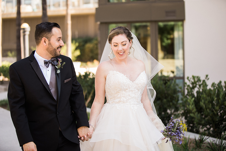 Avenue-of-the-arts-wedding-bride-and-groom-walking-away-bride-in-tulle-ball-gown-with-beaded-bodice-and-beaded-headband-groom-inblack-tuxedo-with-a-silver-vest-and-silver-bowtie