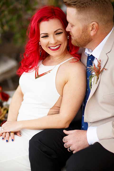 Desert-view-tower-bride-and-groom-close-up-smiling-bride-in-a-fitted-satin-dress-with-a-high-neckline-and-hot-pink-hair-groom-in-a-tan-coat-with-black-pants-and-a-blue-tie