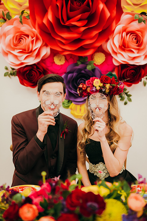 dia-de-los-muertos-drinking-bride-in-a-black-dress-with-floral-headpiece-groom-in-burgundy-tux-with-black-shirt-and-bow-tie