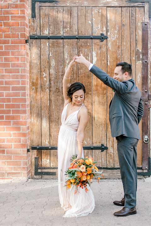 estate-on-second-shoot-bride-and-groom-dancing-bride-wearing-a-flowing-white-gown-with-thin-straps-and-hair-in-a-messy-boho-french-braid-groom-in-a-charcoal-grey-tuxedo-with-a-dark-brown-bow-and-shoes