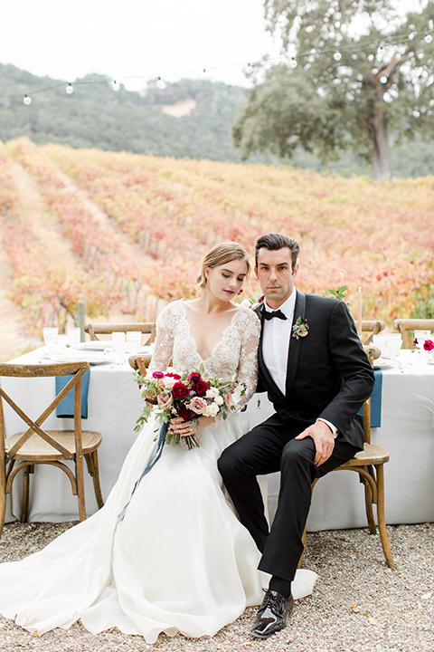 hammersky-editorial-shoot-bride-and-groom-sitting-bride-in-a-tulle-ballgown-with-lace-sleeves-and-high-neckline-groom-in-a-black-shawl-lapel-tuxedo-with-black-bow