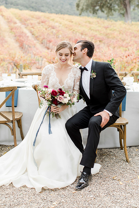 hammersky-editorial-shoot-bride-and-groom-sitting-bride-in-a-tulle-ballgown-with-lace-sleeves-and-high-neckline-groom-in-a-black-shawl-lapel-tuxedo-with-black-bow