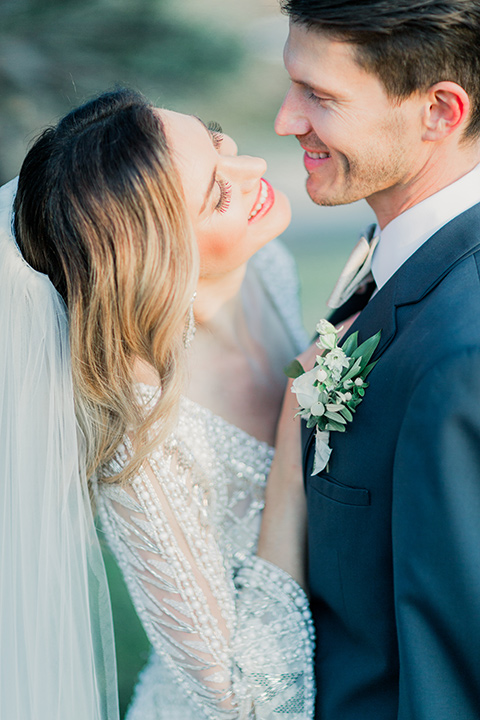 MUCKENTHALER-SHOOT-bride-and-groom-close-up-smiling-bride-in-fitted-satin-long-sleeve-gown-groom-in-a-slate-blue-suit-with-a-ivory-bow-tie