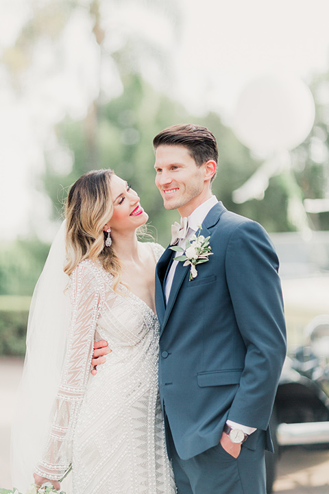 MUCKENTHALER-SHOOT-bride-and-groom-laughing-bride-in-fitted-satin-long-sleeve-gown-groom-in-a-slate-blue-suit-with-a-ivory-bow-tie