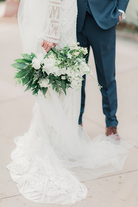 MUCKENTHALER-SHOOT-close-up-on-bride-and-groom-clothing-bride-in-fitted-satin-long-sleeve-gown-groom-in-a-slate-blue-suit-with-a-ivory-bow-tie