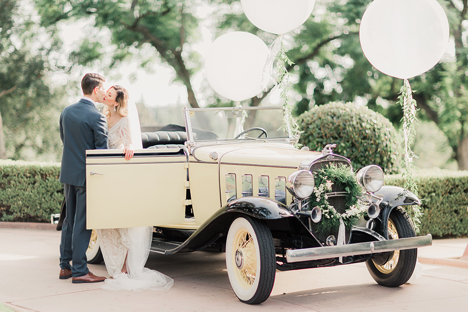 MUCKENTHALER-SHOOT-couple-by-car-bride-in-fitted-satin-long-sleeve-gown-groom-in-a-slate-blue-suit-with-a-ivory-bow-tie