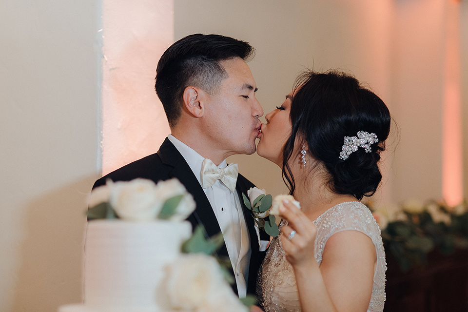 occidental-college-wedding-bride-and-groom-with-cake-groom-in-black-tuxedo-bride-in-a-fitted-gown-with-a-beaded-bodice