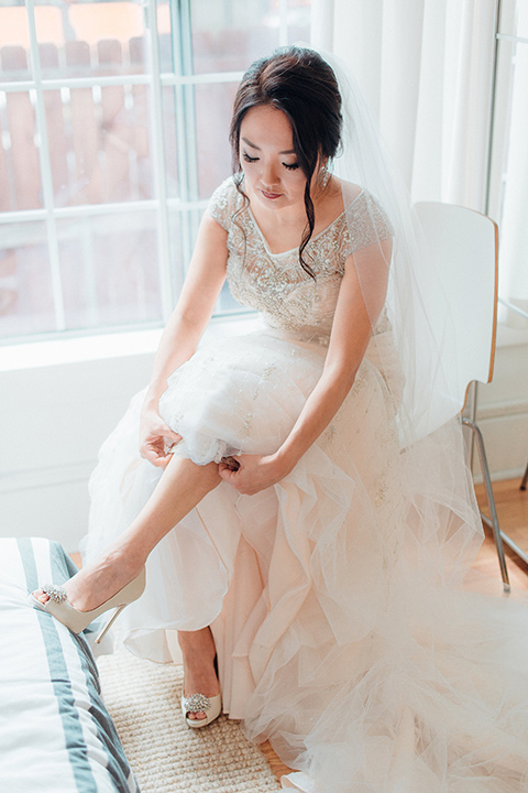 occidental-college-wedding-bride-putting-on-shoes-bride-in-a-fitted-gown-with-a-beaded-bodice