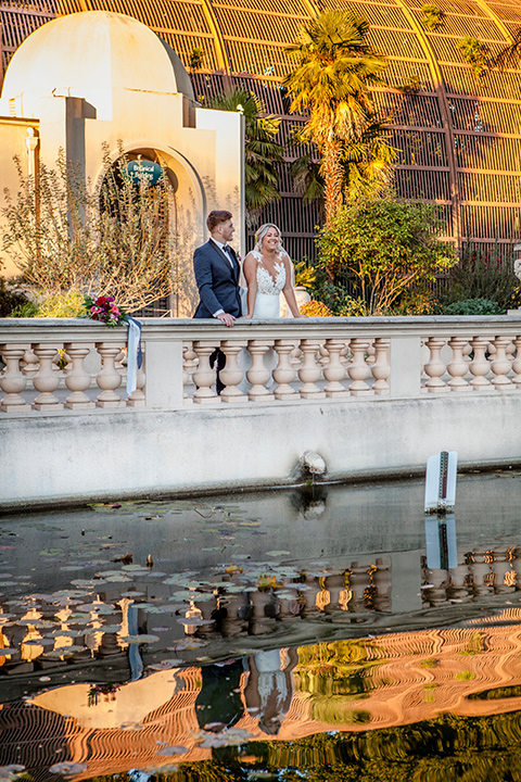 parq-west-shoot-bride-and-groom-on-bridge-bride-wearing-a-flowing-gown-with-an-illusion-lace-bodice-and-cap-sleeves-groom-in-a-charcoal-tuxedo-with-a-black-satin-shawl-lapel