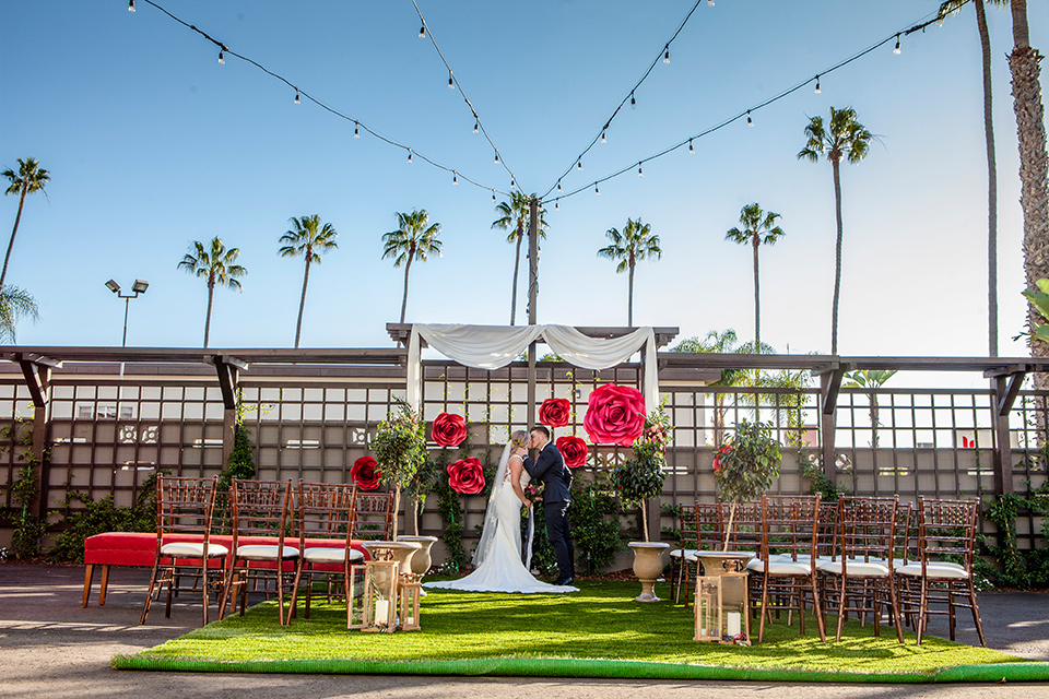 parq-west-shoot-ceremony-space-bride-wearing-a-flowing-gown-with-an-illusion-lace-bodice-and-cap-sleeves-groom-in-a-charcoal-tuxedo-with-a-black-satin-shawl-lapel