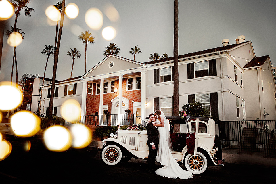 parq-west-shoot-couple-by-car-bride-wearing-a-flowing-gown-with-an-illusion-lace-bodice-and-cap-sleeves-groom-in-a-charcoal-tuxedo-with-a-black-satin-shawl-lapel