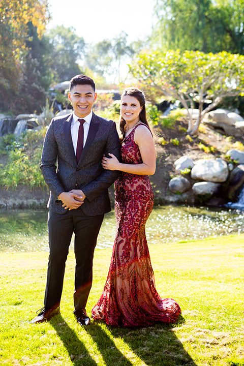 girl-wearing-a-deep-red-prom-dress-boy-wearing-a-charcoal-and-black-paisley-jacket-with-black-pants