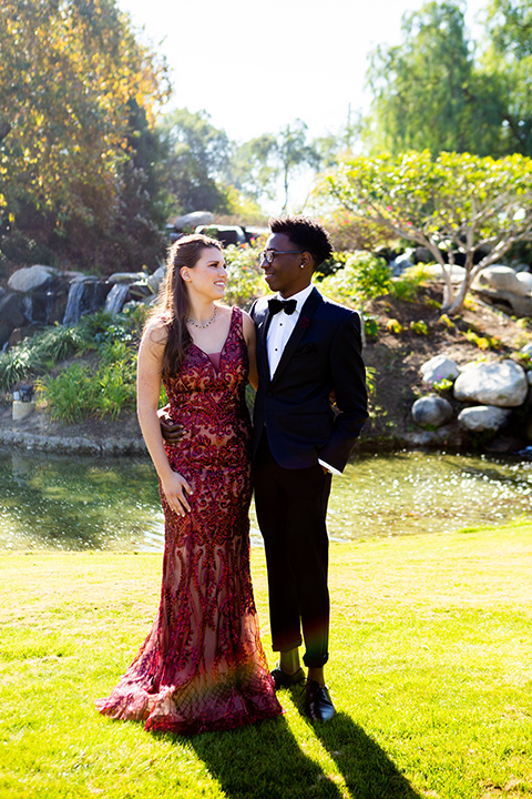 girl-wearing-a-deep-red-prom-dress-and-boy-wearing-a-navy-shawl-lapel-tuxedo-with-navy-pants