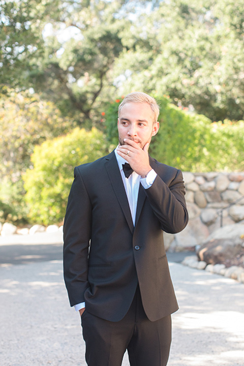 rockwood-shoot-groom-standing-with-hand-in-pocket-and-hand-to-mouth-groom-in-a-simple-black-tuxedo-with-black-bow-tie-and-white-shirt