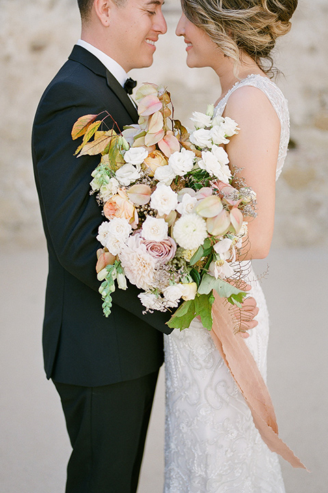 san-juan-capastrano-wedding-bride-and-groom-about-to-kiss-bride-in-a-white-fitted-silk-dress-with-cap-sleeves-and-an-illusion-neckline-and-back-groom-in-a-black-tuxedo-with-black-bow-tie