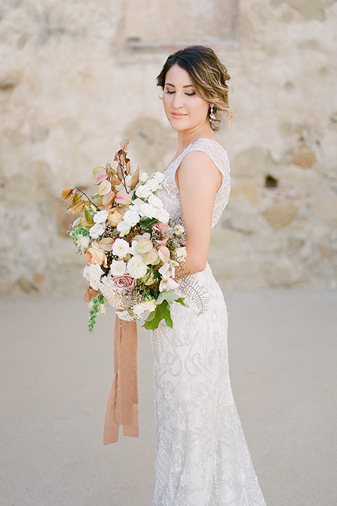 san-juan-capastrano-wedding-bride-looking-down-bride-in-a-white-fitted-silk-dress-with-cap-sleeves-and-an-illusion-neckline-and-back