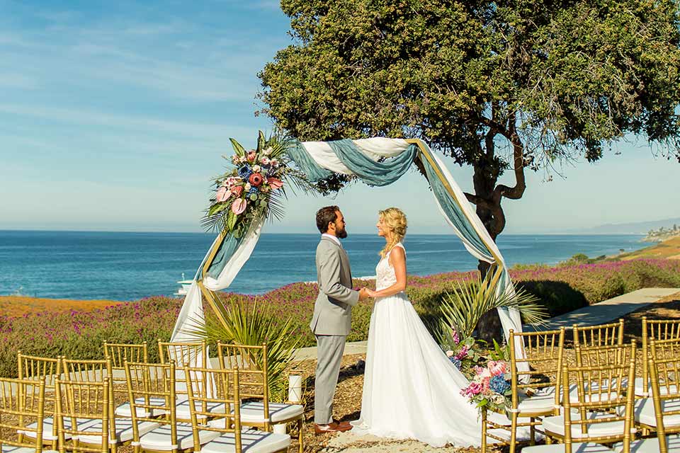 resized-image-seapoint-bridal-shoot-ceremony-bride-in-a-lace-gown-with-thick-lace-straps-and-hair-in-a-loose-braid-groom-in-a-light-grey-suit-with-a-white-long-tie