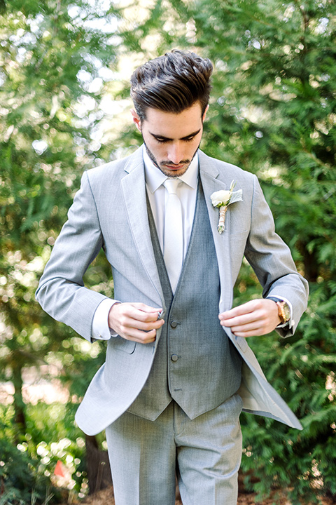 skypark-styled-shoot-groom-putting-on-jacket-groom-in-grey-suit-with-brown-shoes-and-ivory-long-tie