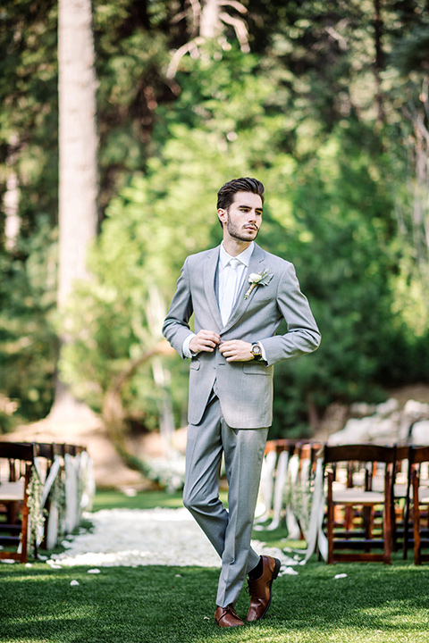 skypark-styled-shoot-groom-standing-groom-putting-on-jacket-groom-in-grey-suit-with-brown-shoes-and-ivory-long-tie