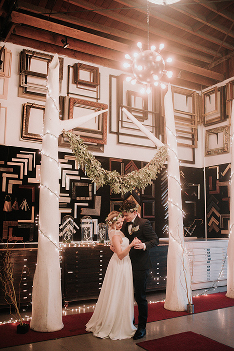 Voila-studios-bride-and-groom-dancing-bride-in-a-flowing-gown-with-a-natural-waistline-and-an-illusion-neckline-with-a-floral-crown-groom-in-a-navy-tuxedo-with-a-leather-bow-tie