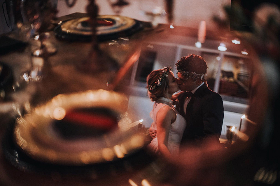 Voila-studios-bride-and-groom-kissing-with-table-scape