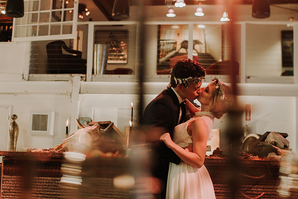 Voila-studios-bride-and-groom-kissing-bride-in-a-flowing-gown-with-a-natural-waistline-and-illusion-neckline-and-floral-crown-groom-in-a-navy-tuxedo-with-leather-bow-tie