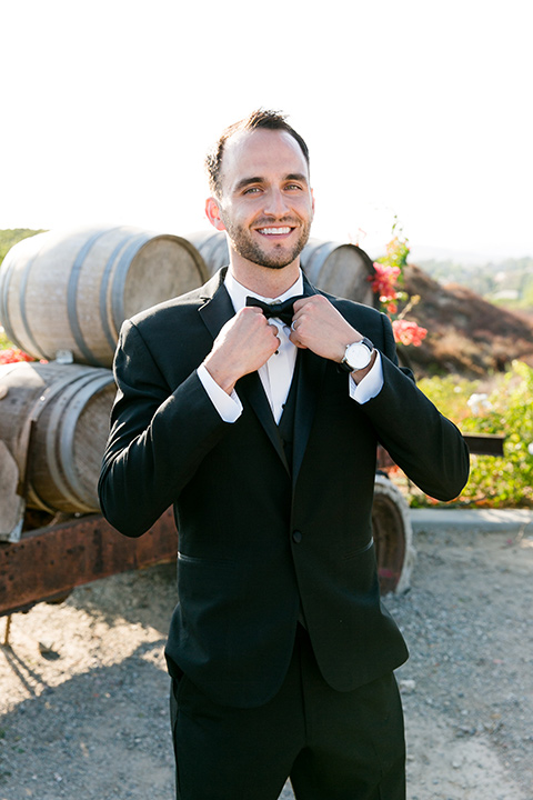 Villa-de-Amore-groo-looking-at-camera-touching-bow-tie-groom-in-a-black-tuxedo