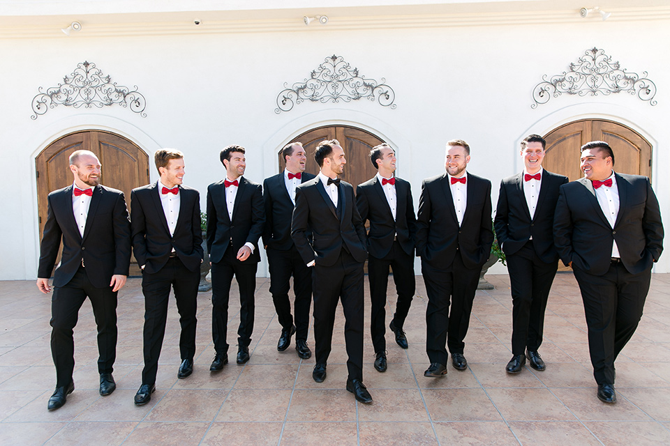Villa-de-Amore-groomsmen-walking-towards-camera-groom-in-black-tuxedo-with-black-bow-tie-and-groomsmen-in-black-tuxedo-with-red-bow-tie