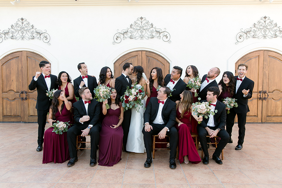 villa-de-Amore-bridalparty-bride-in-a-strapless-gown-with-bridesmaids-in-alternating-red-dresses-groom-and-groomsmen-in-black-tuxedos