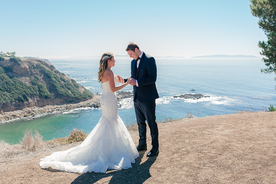 Los-Verdes-Golf-Course-Wedding-bride-and-groom-first-look-bride-is-in-a-lace-mermaid-style-gown-with-a-modified-sweetheart-neckline-the-groom-is-in-a-navy-blue-tuxedo-with-a-black-shawl-lapel-and-a-black-bow-tie