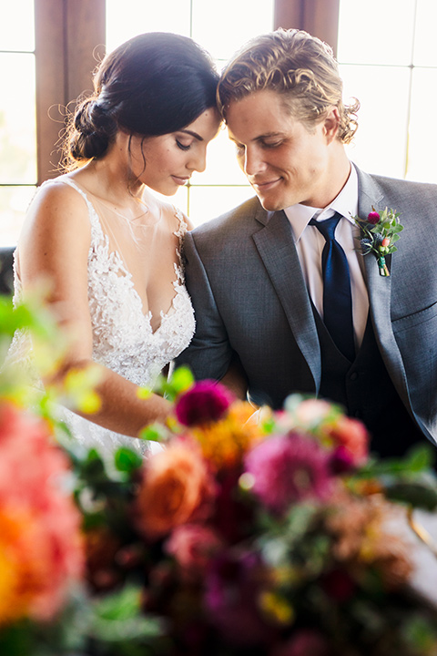 aliso viejo wedding design with the bride in a lace white gown with thin straps and a full skirt and the groom in a grey suit and navy neck tie