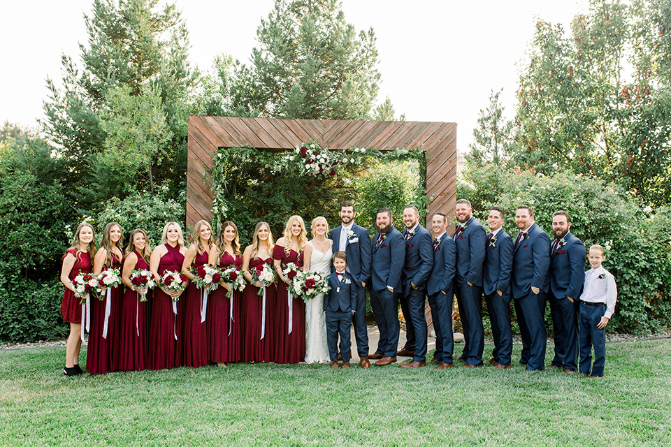 Burgundy-and-Blue-wedding-bridalparty-brdesmaids-in-burgundy-gowns-groomsmen-in-dark-blue-suits-bride-in-a-formfitting-white-lace-gown-with-a-strapless-neckline-the-groom-is-in-a-dark-blue-suit-with-an-ivory-long-tie