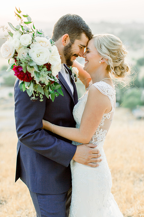 Burgundy-and-Blue-wedding-bride-and-groom-touching-heads-bride-in-a-lace-white-gown-with-a-sweetheart-neckline-groom-in-a-dark-blue-suit-with-a-white-tie