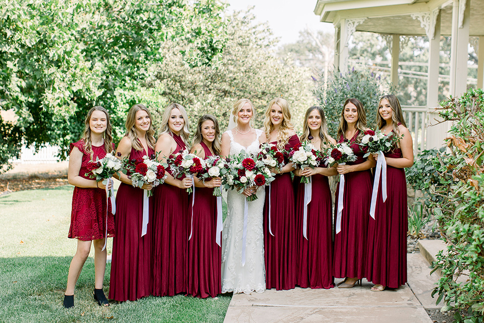 Burgundy-and-Blue-wedding-bridesmaids-dresses-bride-in-a-formfitting-white-lace-gown-with-a-strapless-neckline-bridesmaids-in-deep-burgundy-gowns