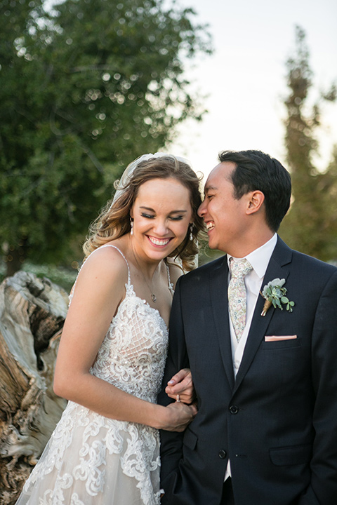 Garden-Wedding-bride-and-groom-hugging-bride-in-a-strapless-white-ballgown-and-the-groom-in-a-navy-suit-with-a-white-long-tie-and-pink-pocket-square