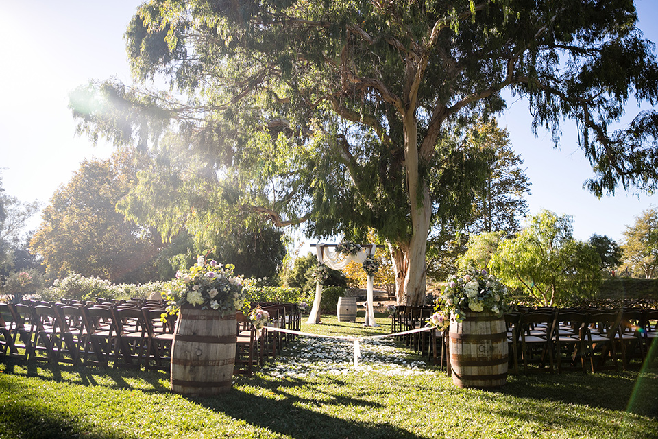 Garden-Wedding-ceremony-décor-with-wooden-chairs-and-an-arch-with-a-drapping-white-fabric