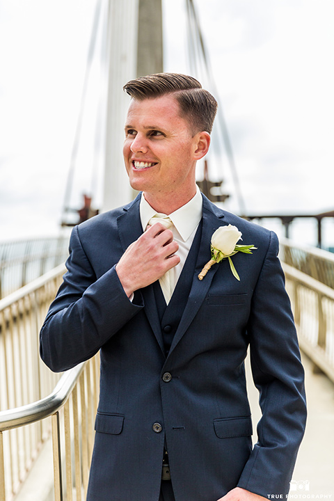 Groom fixing white tie in a navy blue suit