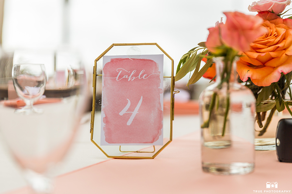 wedding table number cards on wooden picnic tables with coral details