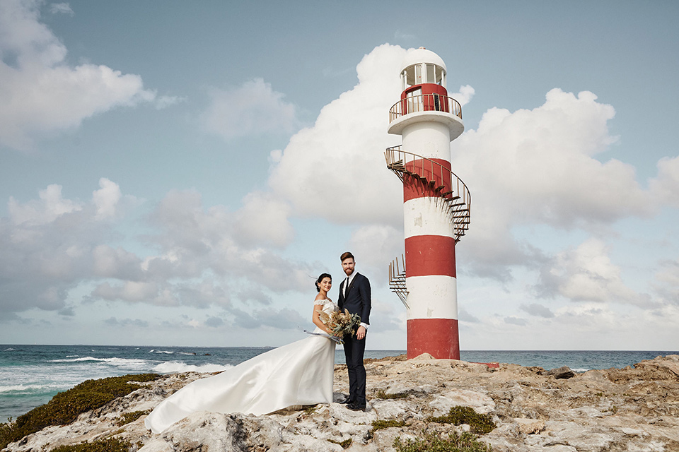 Grand-Firesta-Americana-Coral-Beach-bride-and-groom-by-lighthouse-bride-in-ballgown-groom-innavy-tuxedo